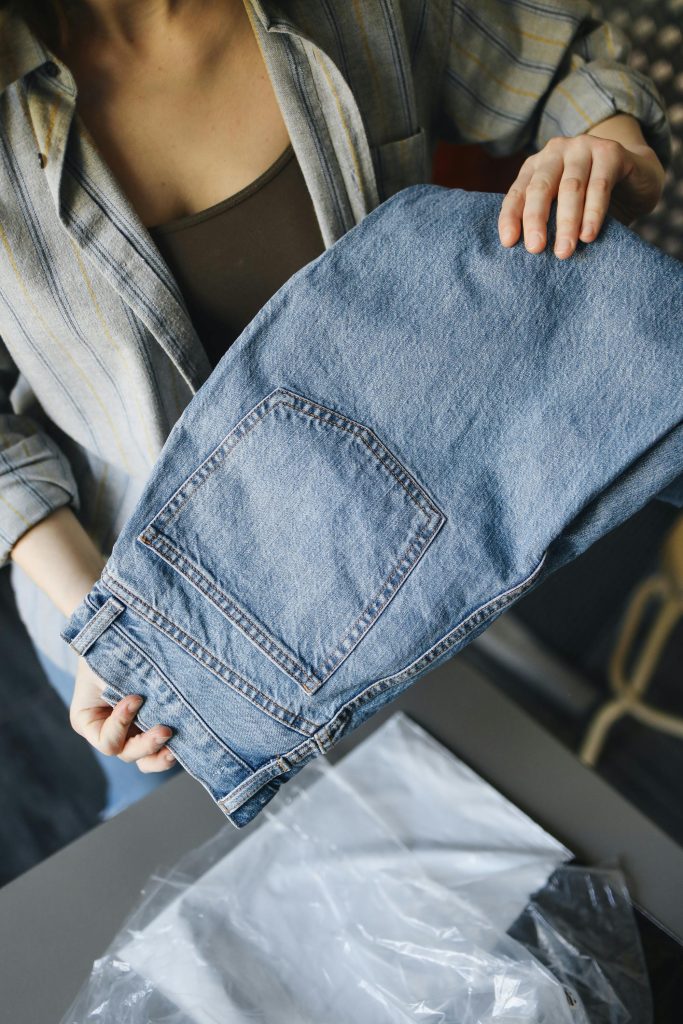 Close-up of a woman holding a folded pair of denim jeans, highlighting casual fashion.